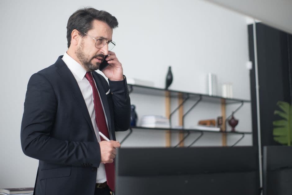 Businessman speaking urgently on the phone in a modern office, representing the time-sensitive response required during Amazon's Account Health Assurance window