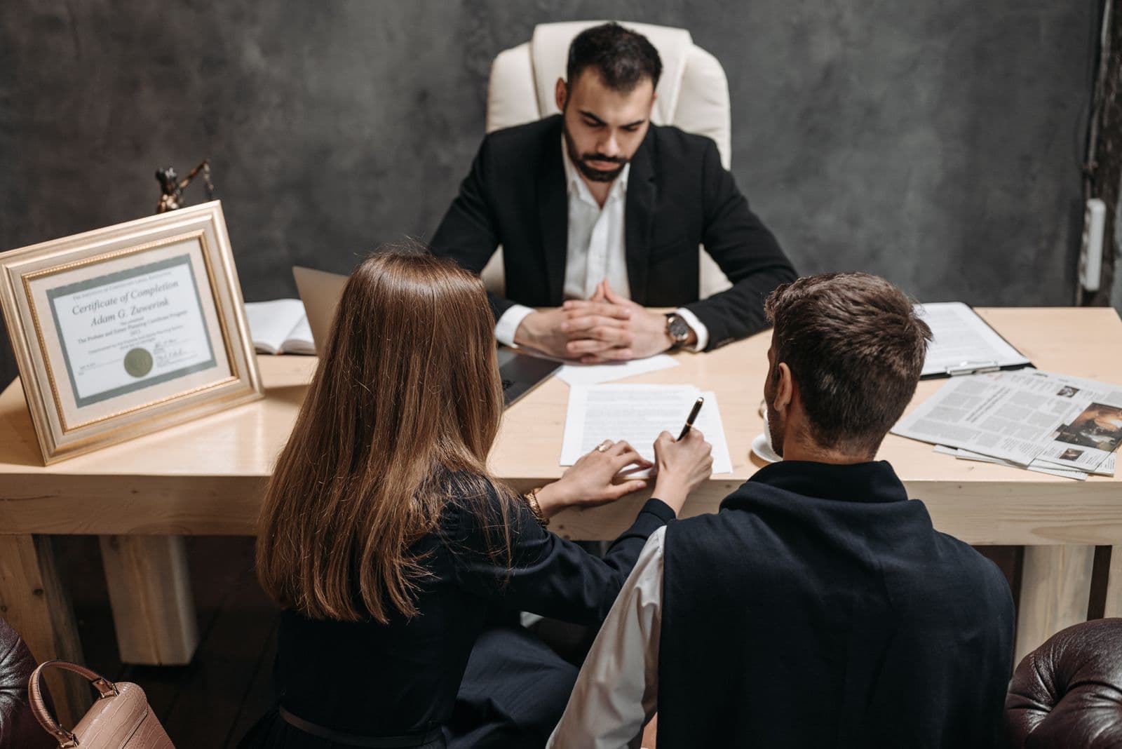 A lawyer discussing legal documents with clients across a desk in an office.