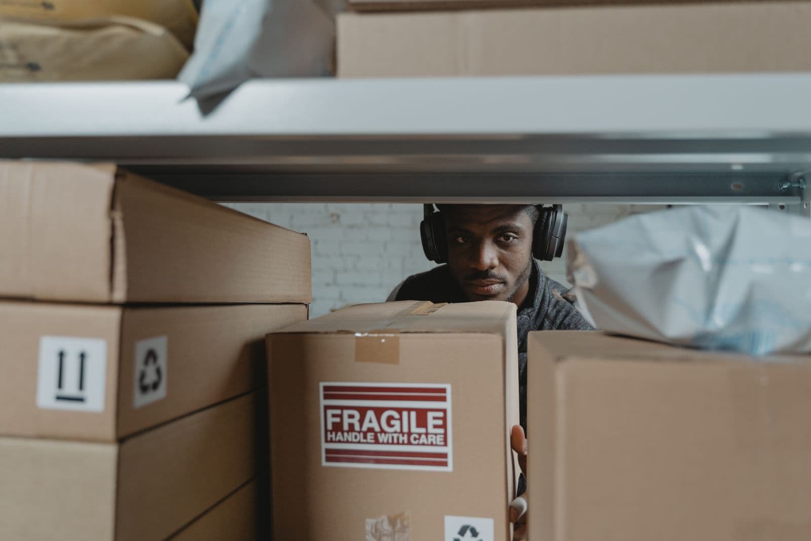 A warehouse worker inspecting a fragile cardboard shipment box.