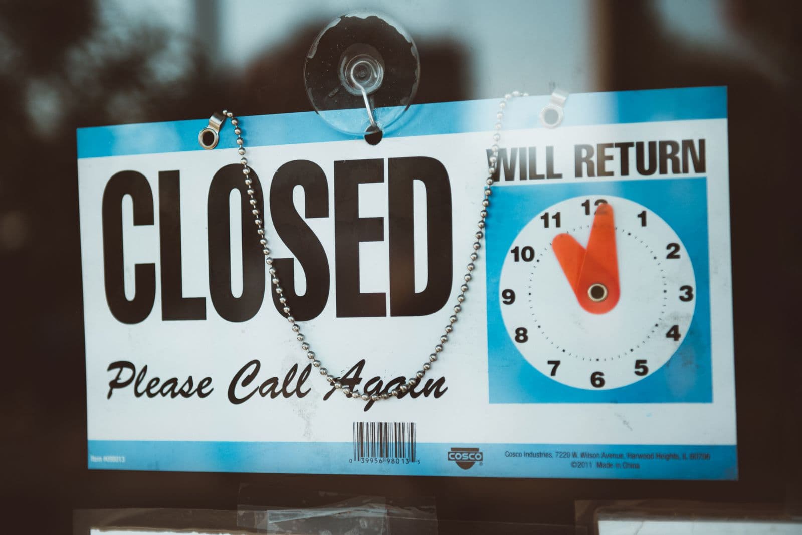 A "Closed, please call again" sign hanging on a glass door.