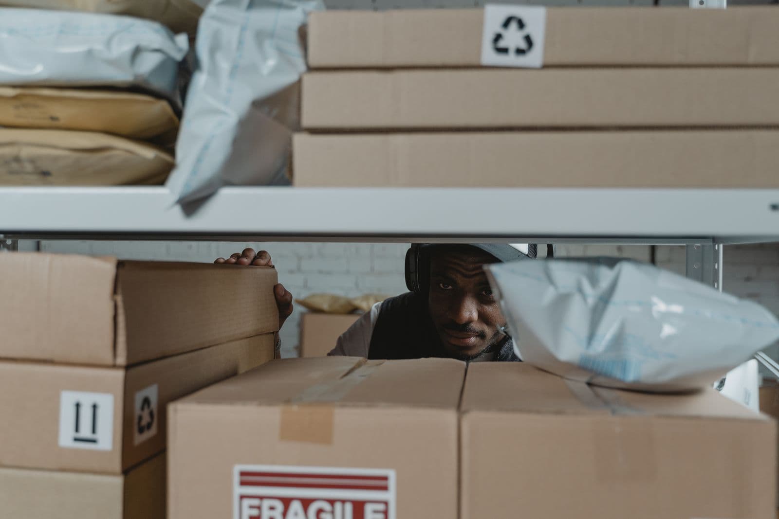 A warehouse worker inspecting shipment packages on shelves for quality and accuracy.