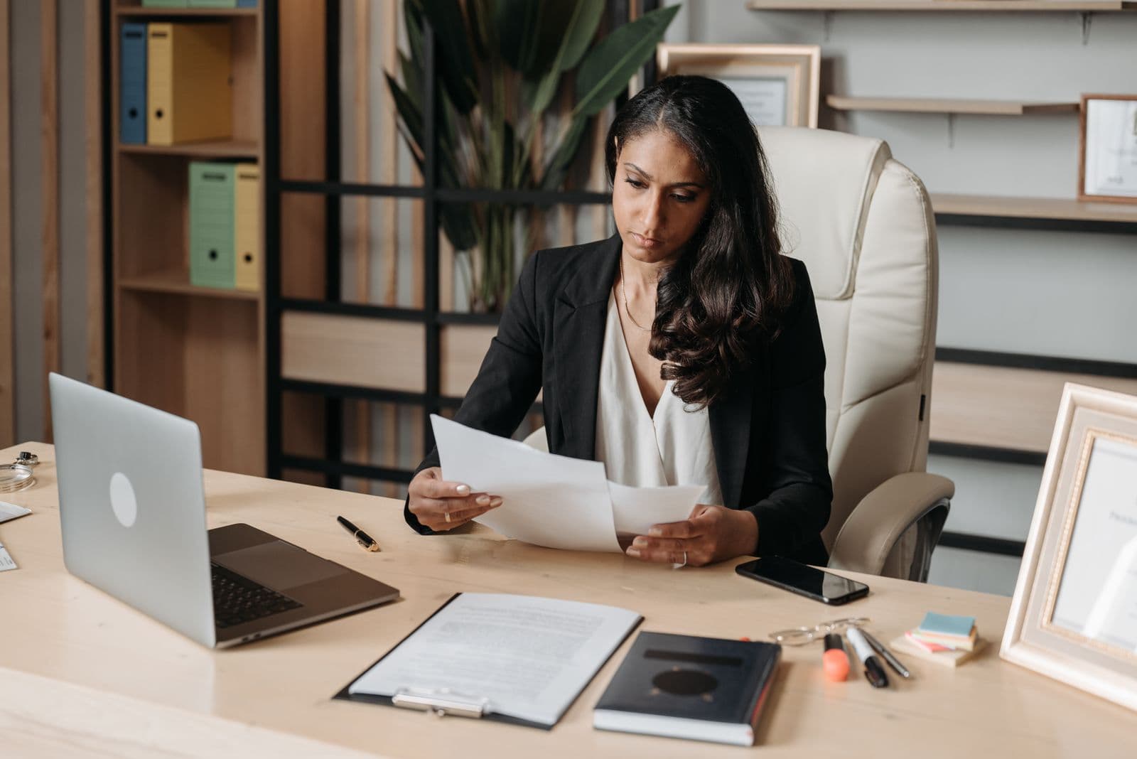 A person at an office desk reviewing printed documents closely